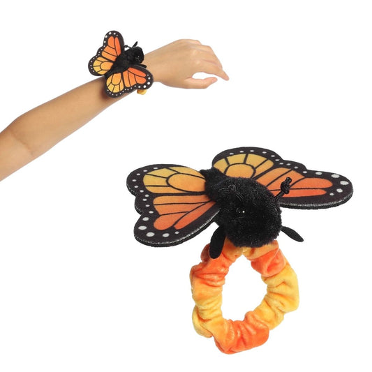 A person's arm wearing the 5-inch Aurora Wrist Flingers Monarch Butterfly plush with a close-up of the classic orange and black butterfly toy.