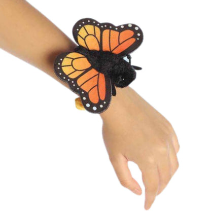 A child's arm outstretched, showing how the Monarch butterfly plush accessory looks when worn.