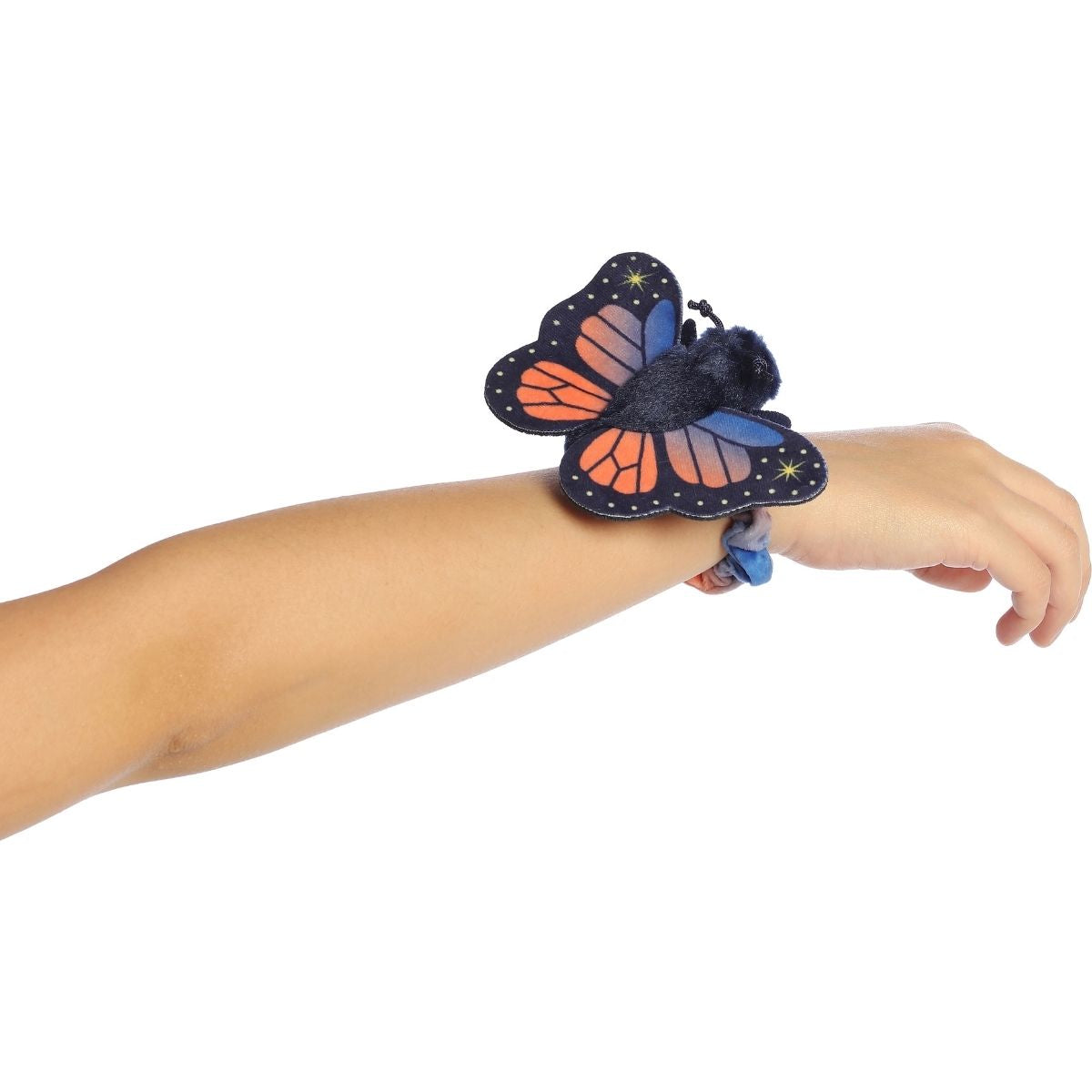 A child's arm outstretched, wearing the dark blue and orange butterfly plush securely on their wrist.
