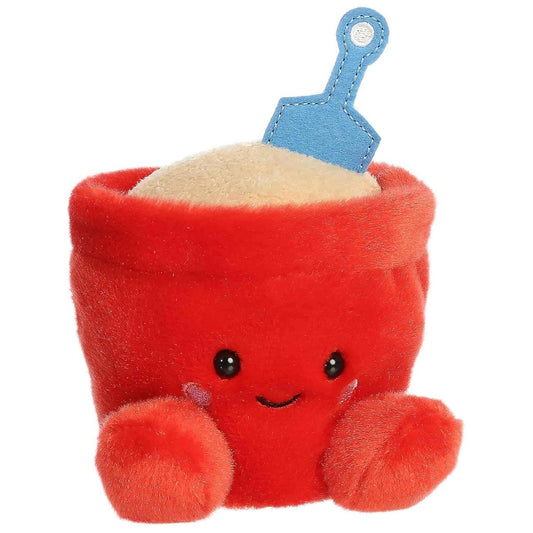 Front-angled view of the Aurora Palm Pals June Sand Bucket 5-inch stuffed animal featuring a red bucket body, smiling face, plush sand, and a blue shovel.