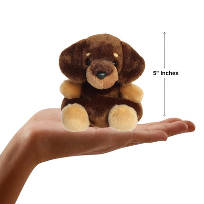 A hand holding the Aurora Palm Pals Houdini Dachshund plush, demonstrating its small, 5-inch palm-sized design.