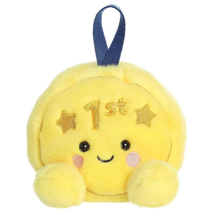 Straight-on look at the gold medal plushie displaying its cheerful embroidered smile and tiny yellow feet.