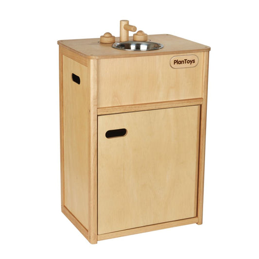 Front angle of the eco-friendly PlanToys wooden play sink featuring a metal basin, wooden faucet, and closed cabinet.