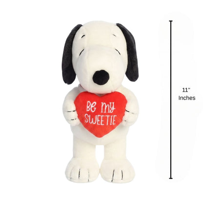 The holiday Snoopy plush standing upright next to an 11-inch vertical height graphic indicator.