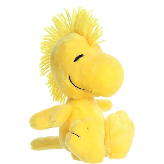 Front angled view of the 6.5-inch Aurora Peanuts Floppy Woodstock plush toy featuring bright yellow fur and a fuzzy tuft of hair.