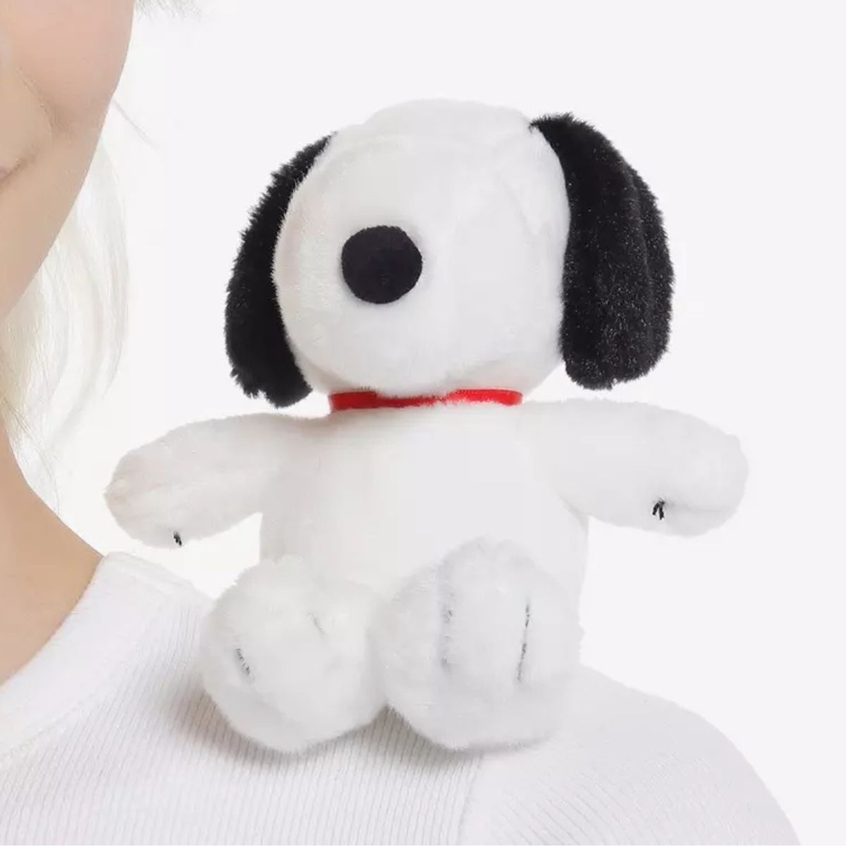 The 5-inch Aurora Peanuts Shoulderkins Snoopy plush sitting securely on a person's shoulder, highlighting his red collar.