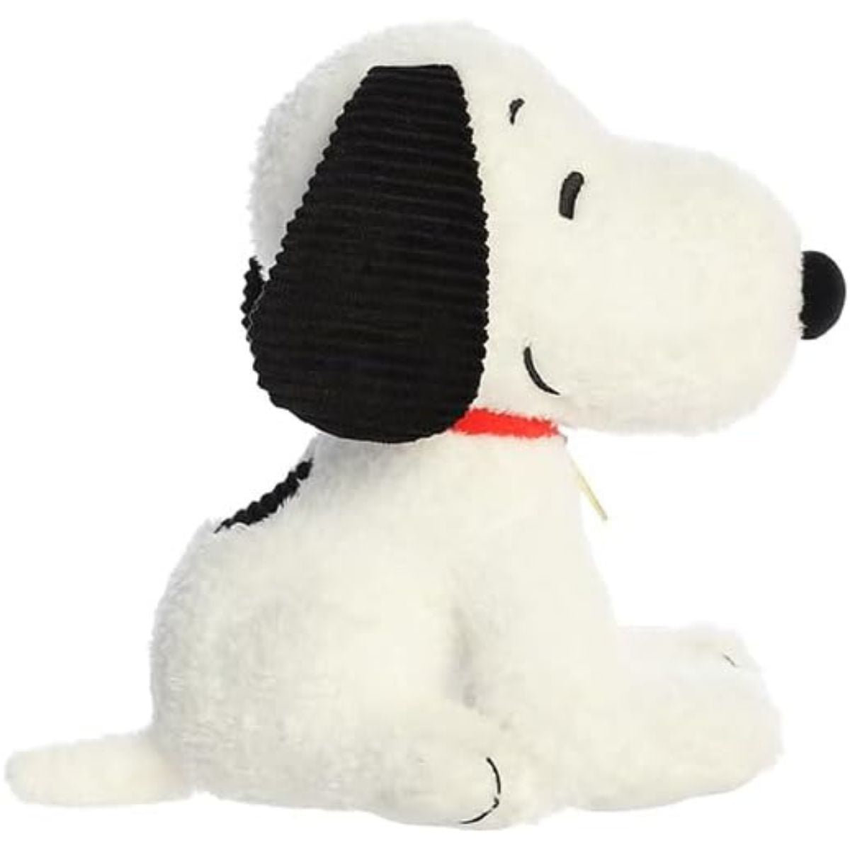 Side profile view of the cuddly Snoopy plush sitting comfortably, highlighting his red collar and gold tag.