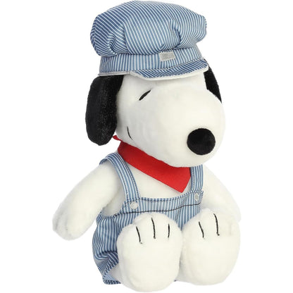 Angled front view of the 14-inch Aurora Peanuts Train Engineer Snoopy stuffed animal sitting down wearing striped overalls, a matching hat, and a red neckerchief.
