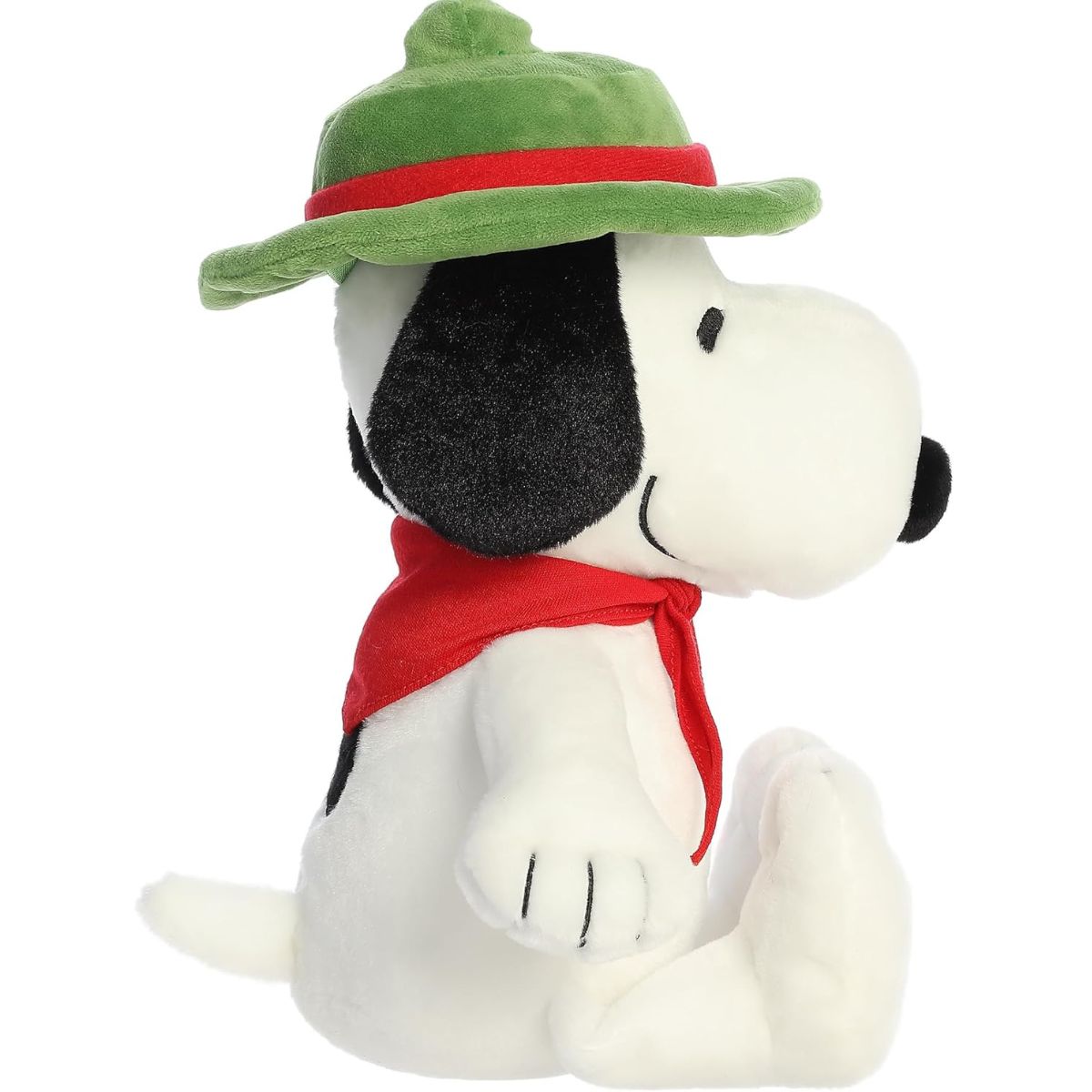 Side profile view of the cuddly Snoopy plush sitting comfortably, highlighting his red neckerchief tie and green hat.