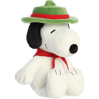 Angled front view of the 12-inch Aurora Peanuts Beagle Scout Snoopy stuffed animal sitting down wearing his green hat and red neckerchief.