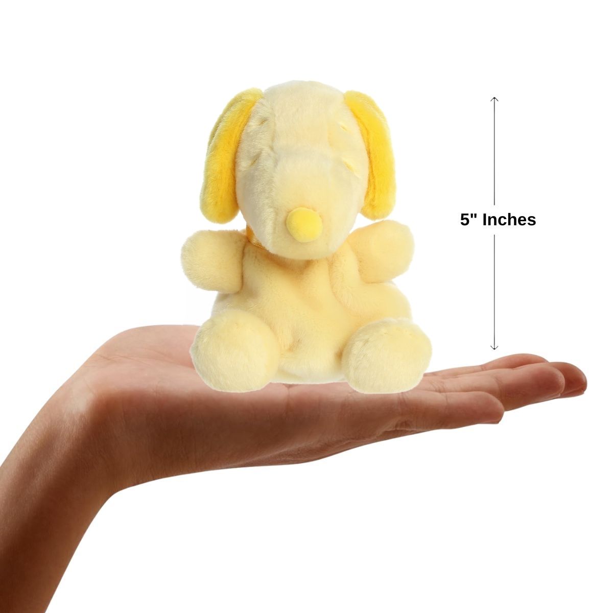 Sizing graphic showing the 5-inch Palm Pals Yellow Snoopy plush sitting perfectly in the palm of a hand to demonstrate its small scale.