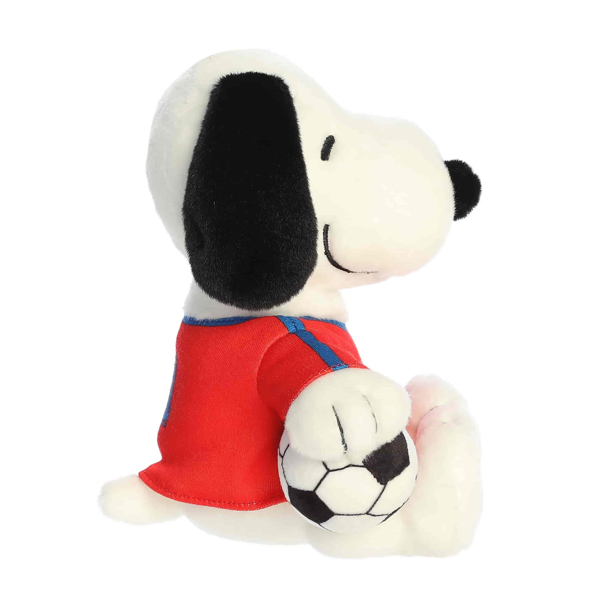 Side profile view of the Snoopy soccer plush highlighting his floppy black ear and the soccer ball tucked under his arm.