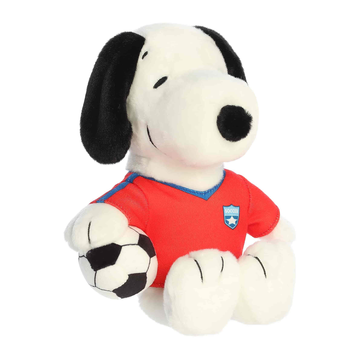Front angled view of the 8-inch Aurora Peanuts Soccer Snoopy plush toy sitting down, wearing a red soccer jersey and holding a black and white soccer ball.