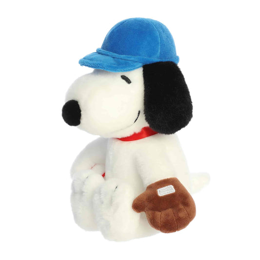 Front angled view of the 9-inch Aurora Peanuts Baseball Snoopy plush toy sitting down, wearing a blue baseball cap and a brown glove.