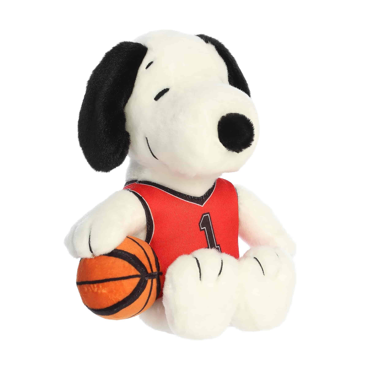Front angled view of the 8-inch Aurora Peanuts Basketball Snoopy plush toy sitting down, wearing a red jersey and holding an orange basketball.