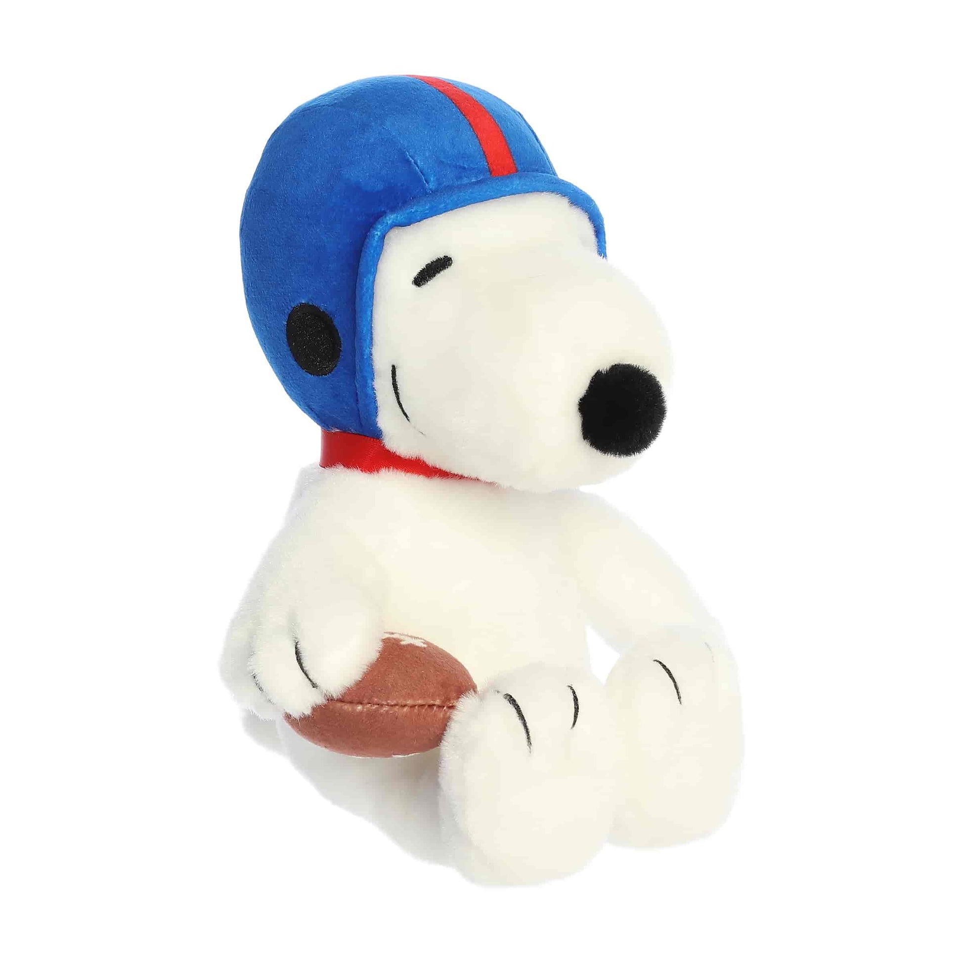 Front angled view of the 8-inch Aurora Peanuts Football Snoopy plush toy sitting down, wearing a blue helmet and holding a football.