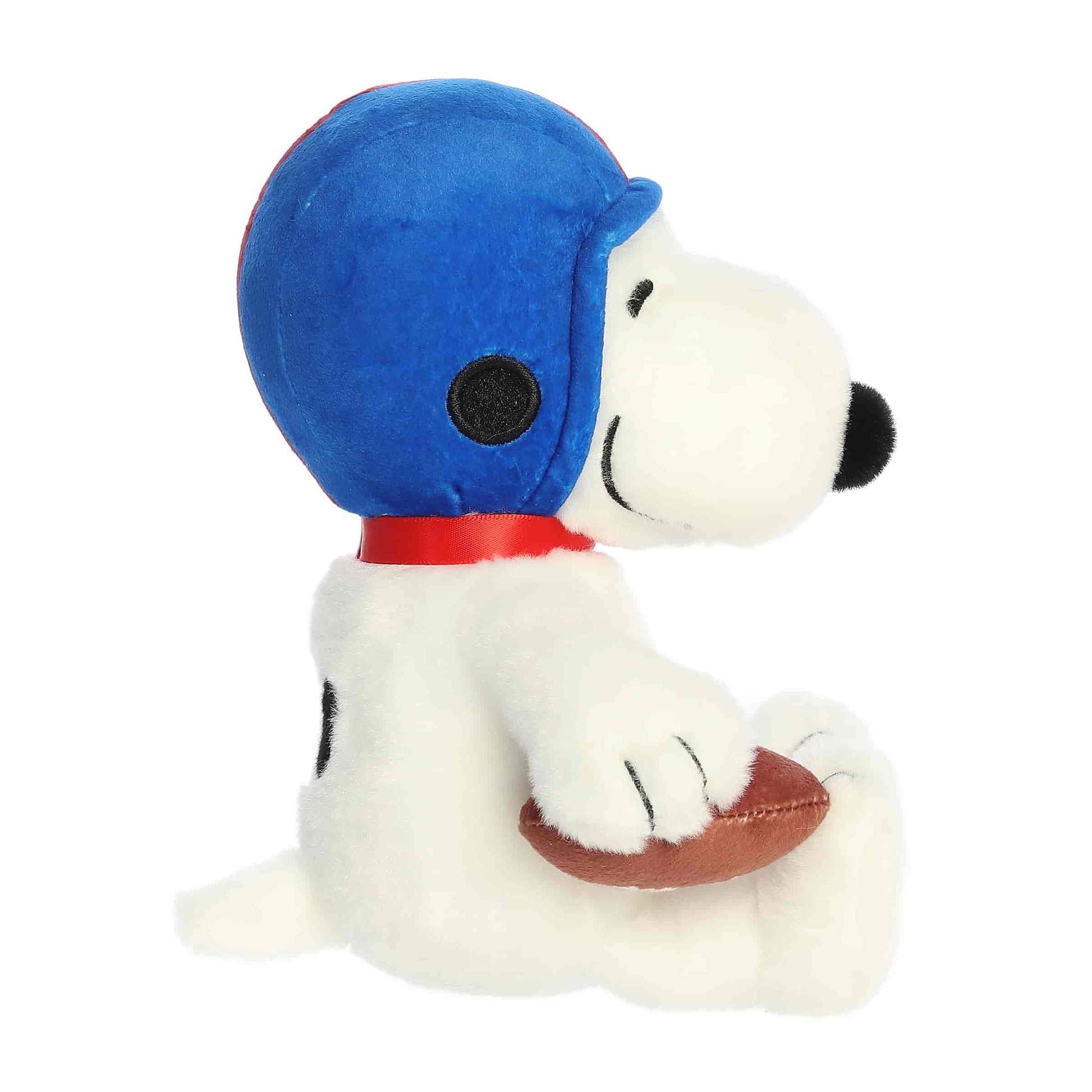 Side profile view of the Snoopy football plush highlighting his blue helmet, floppy black ear, and the football tucked under his arm.