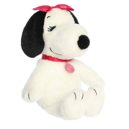 Front-angled view of the Aurora Peanuts Belle 8-inch stuffed animal featuring her pink bow, pink collar, and long eyelashes.