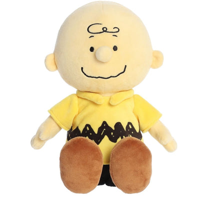 Angled front view of the soft Charlie Brown plush sitting upright in his classic yellow zig-zag shirt.