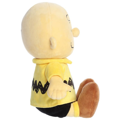 Side profile view of the Aurora Peanuts Charlie Brown plush sitting with his brown shoes extended.