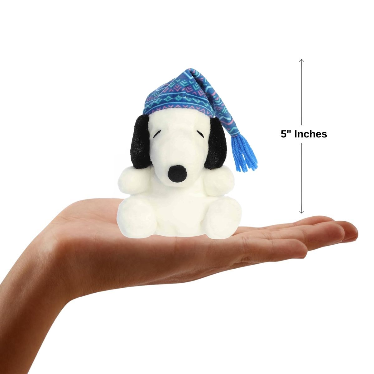 A hand holding the Aurora Palm Pals sleepy Snoopy plush, demonstrating its small, 5-inch palm-sized design.