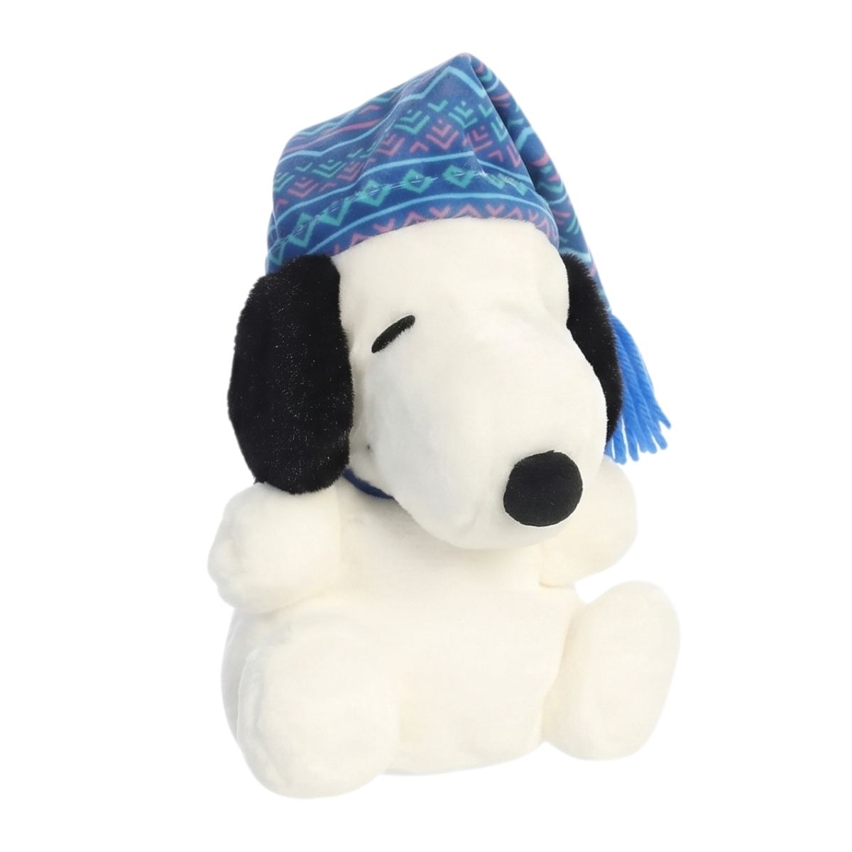 Front angled view of the Aurora Palm Pals Peanuts Snoopy plush with closed sleepy eyes, wearing a blue patterned winter hat with a tassel.