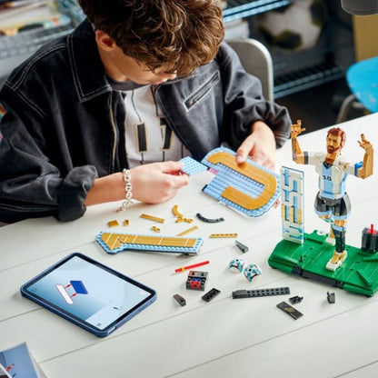 A builder using a digital tablet layout next to scattered pieces to assemble the LEGO® Lionel Messi set.