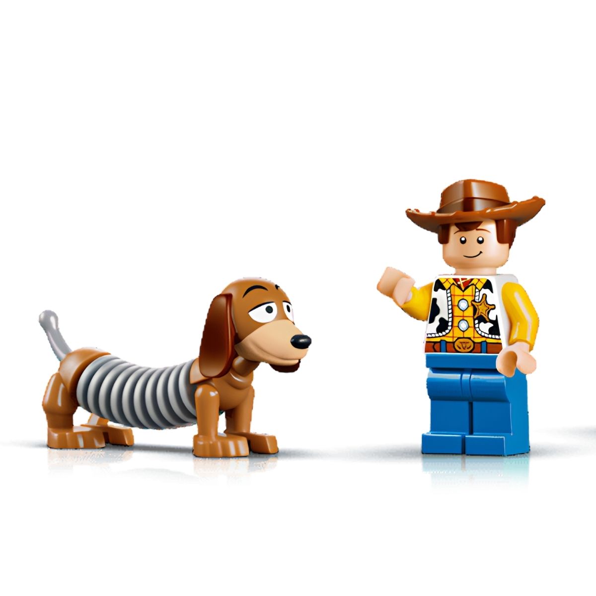 Close-up shot of the included LEGO® Woody minifigure standing next to the completed Slinky Dog brick figure.