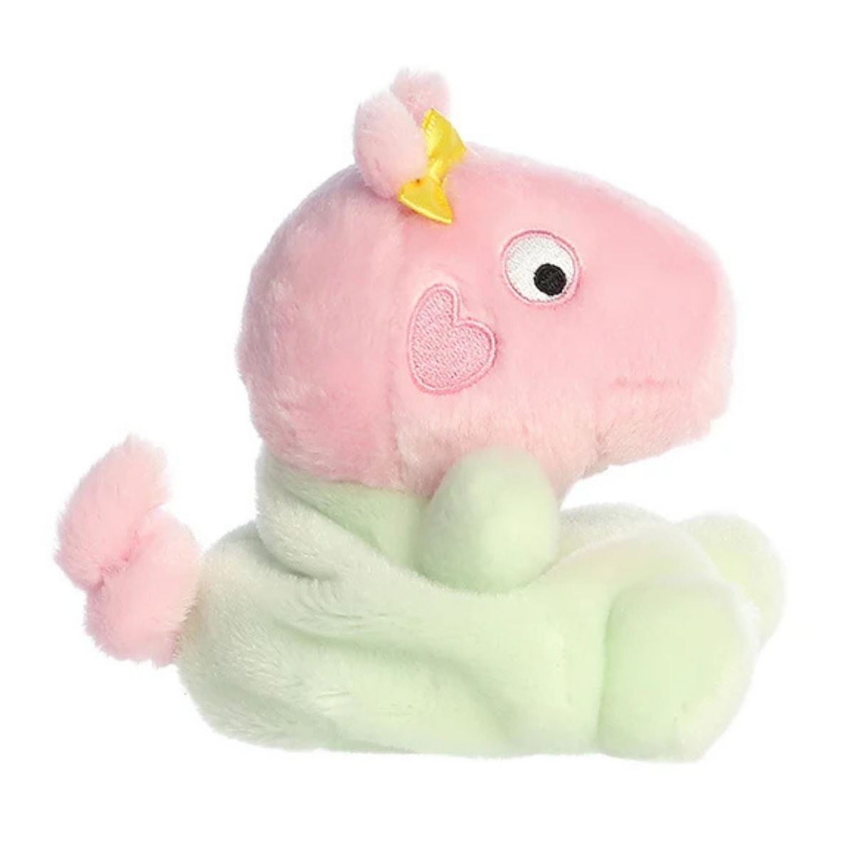 Side profile view of the Palm Pals Baby Evie highlighting her plump shape, yellow bow, and little curly pink tail.