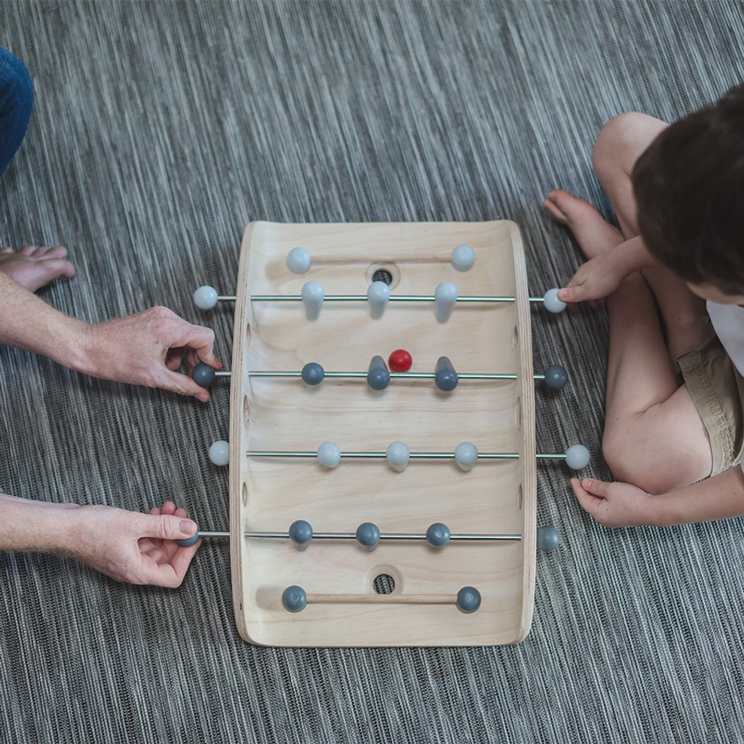 Overhead lifestyle shot of two players competing in a fast-paced game of PlanToys tabletop foosball.