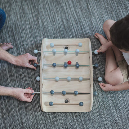 Overhead lifestyle shot of two players competing in a fast-paced game of PlanToys tabletop foosball.