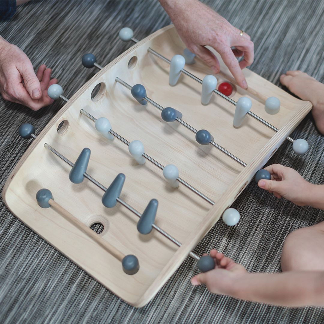 Close-up of hands actively spinning the wooden figures to block the red ball during a PlanToys soccer match.