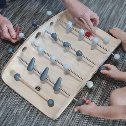 Close-up of hands actively spinning the wooden figures to block the red ball during a PlanToys soccer match.