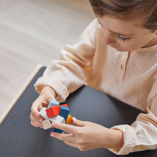 A child engaging in quiet, focused play with the PlanToys travel-friendly wooden puzzle.