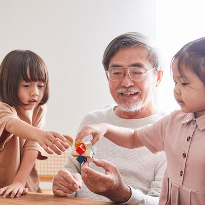 Close-angle of a toddler and adult enjoying a bonding moment while building the PlanToys sustainable wooden puzzle.