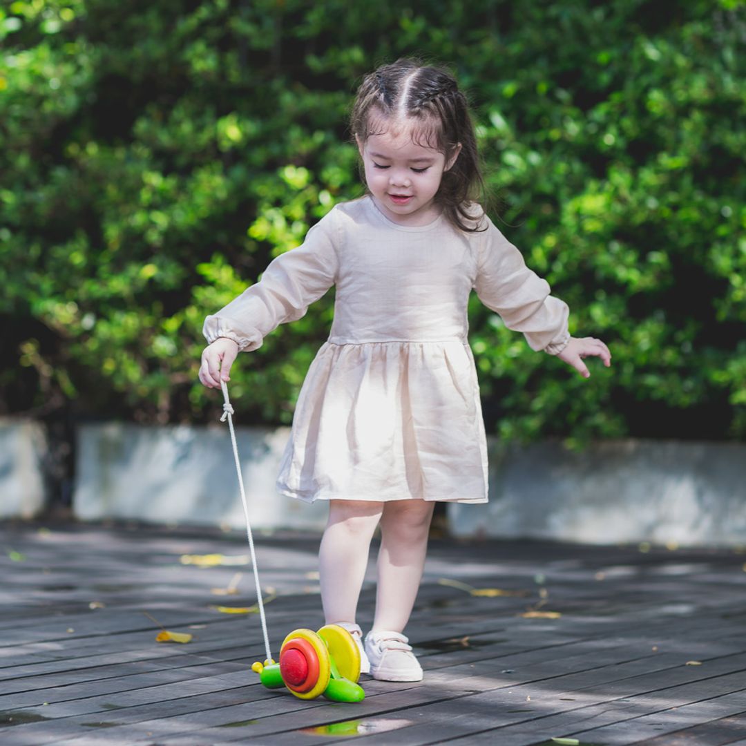 Child engaging and pulling the PlanToys wooden pull-along snail toy 
