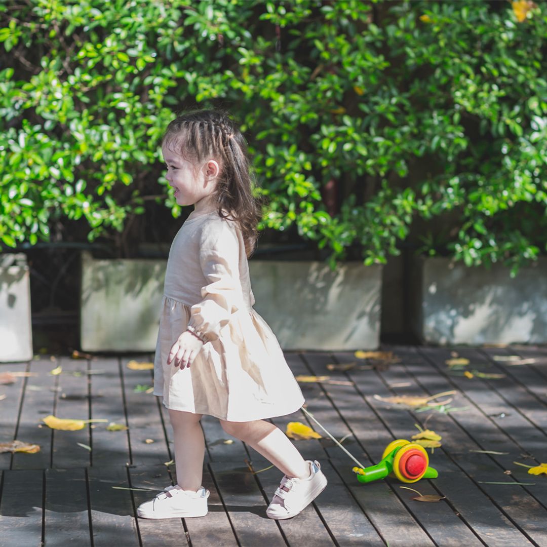 Child pulling the PlanToys wooden pull-along snail toy across the floor.