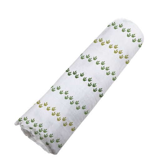 Angled view of the white and green Dino Feet print cotton muslin swaddle blanket neatly rolled up.