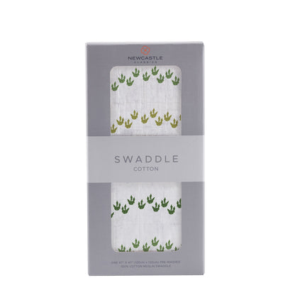Straight front view of the packaged Dino Feet baby swaddle blanket in a grey Newcastle Classics box.
