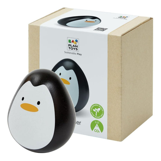 The eco-friendly PlanToys wooden penguin wobbler toy displayed next to its sustainable cardboard packaging.