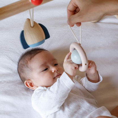 Close angle of a baby exploring the textures of the non-toxic, water-based finish on the PlanToys gym.