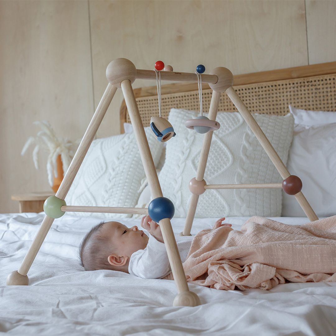 Detailed lifestyle shot highlighting an infant playing with the PlanToys gym.