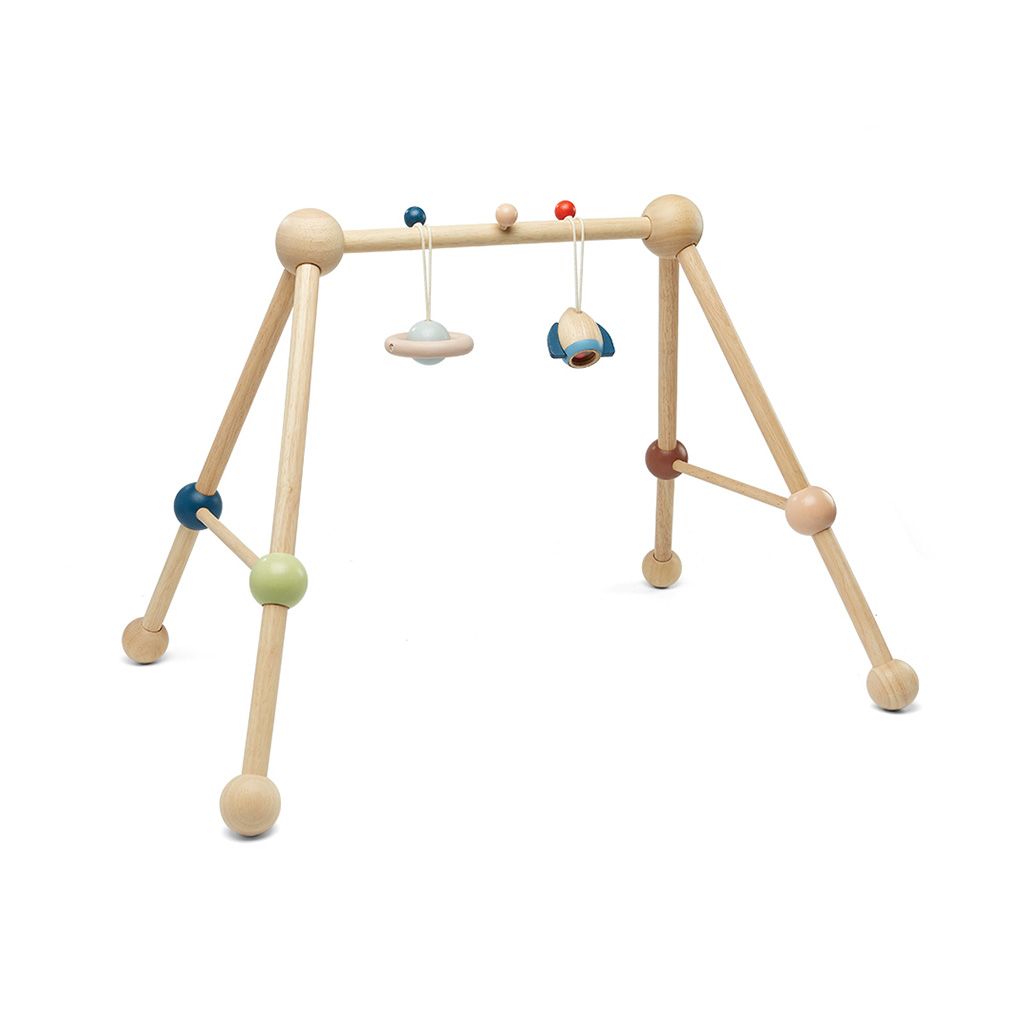PlanToys wooden baby play gym in the Orchard colorway with dangling space toys.