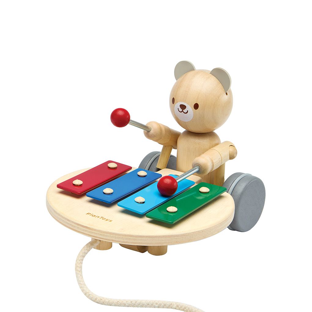 Angled view of the sustainable PlanToys musical bear showing the drumming arm ready to strike the colorful keys.