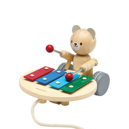 Angled view of the sustainable PlanToys musical bear showing the drumming arm ready to strike the colorful keys.