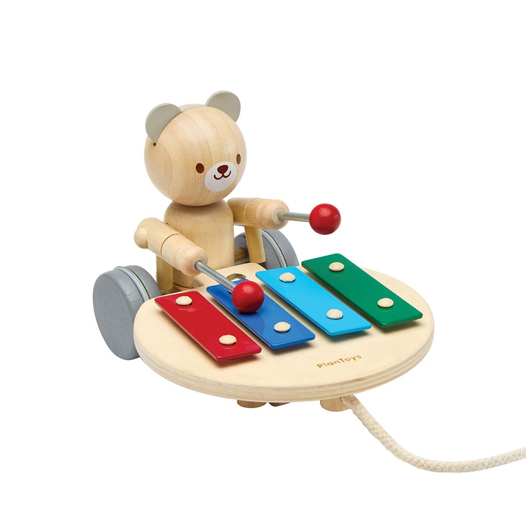 Side view of the durable PlanToys wooden pull toy showcasing the sturdy wheels and drumming arm mechanism.
