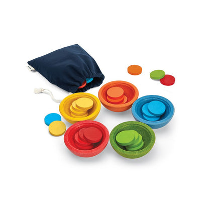 Overhead view of the sustainable PlanToys sort and count set featuring five colored wooden bowls, coins, and a cotton bag.