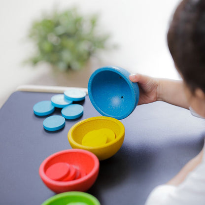 Detailed lifestyle shot of a child holding the smooth, water-based painted blue cup from the PlanToys counting toy.