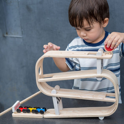 A young boy developing visual tracking skills by watching a car zoom down the non-toxic wooden ramp racer.