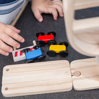 Close-up of the three colorful wooden cars reaching the finish line barrier on the PlanToys racing track.